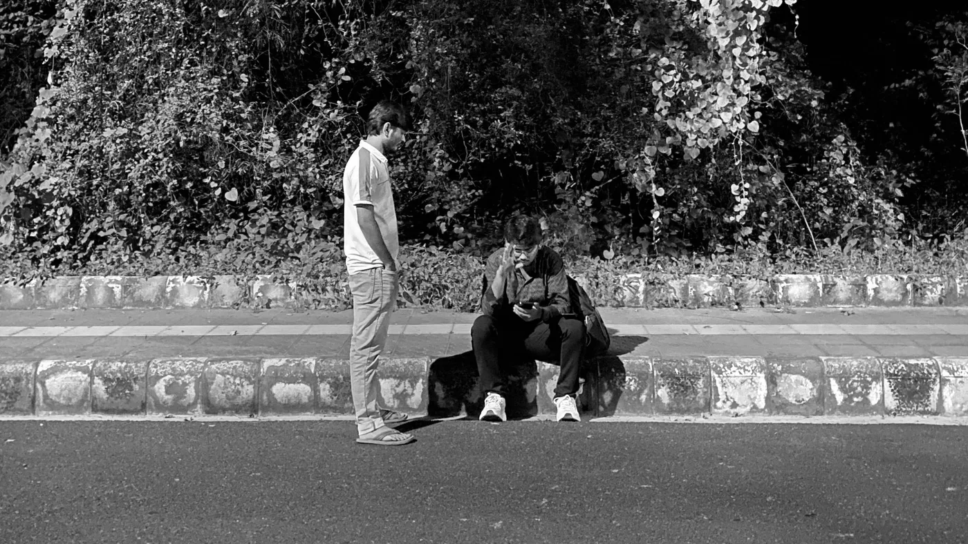 Late night roadside: Faisal on a partner call sitting on the kerb, Asher standing beside him